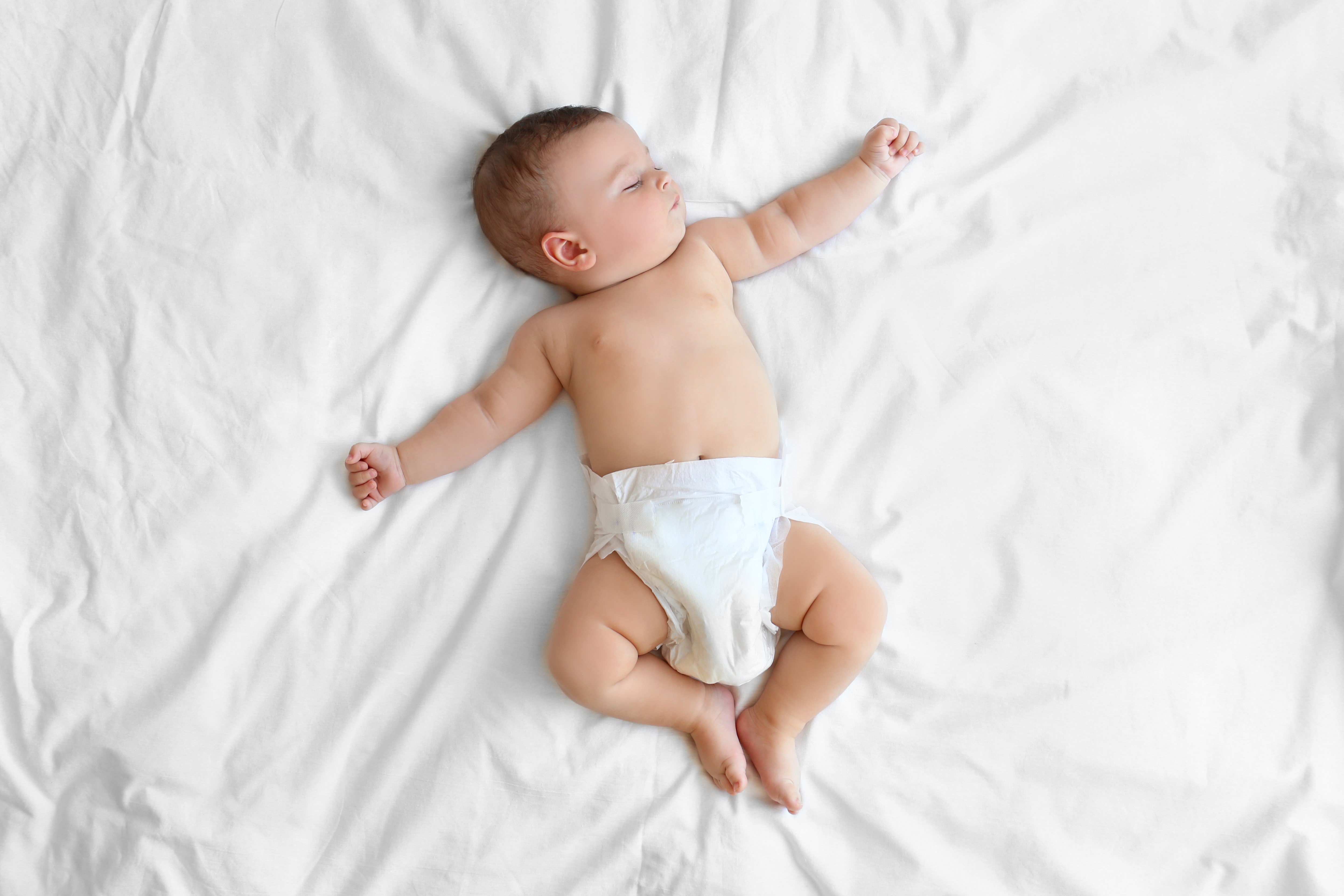 Srčkan dojenček doma spi na postelji